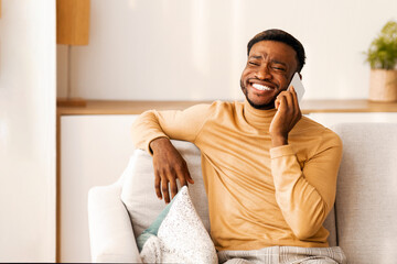 Aufkleber - Cheerful African American Man Talking On Cellphone Sitting On Sofa Indoor. Phone Conversation Concept