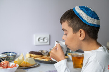 jewish family celebrating hanukkah, israel, boy in kippah, jewish holidays, yom kippur feast, table with food, honey, donuts, family holiday