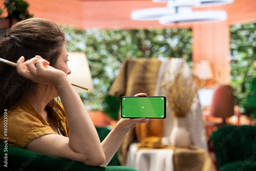 Female artist holding device with green screen in art and craft atelier ...