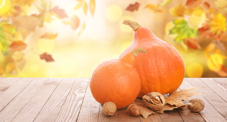 Fresh pumpkins, nuts and autumn leaves on wooden table outdoors