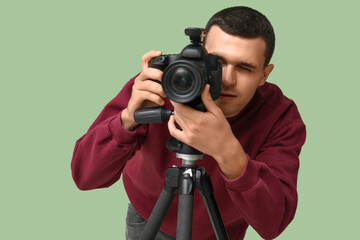 Poster - Male photographer with modern camera on tripod against green background