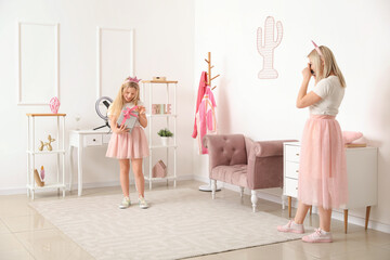 Wall Mural - Beautiful female blogger recording her daughter on camera at home