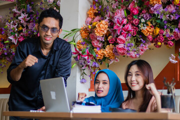 Group of Asian students happy looking at camera successfully solve complicated case from lecturer in front of laptop computer in coffee shop cafe. for group concept, company, education, education