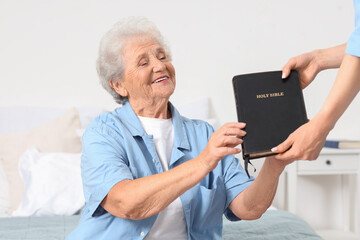 Wall Mural - Caregiver giving Bible to senior woman at home