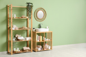 Sticker - Shelving unit with sink, mirror and bath accessories near green wall in room