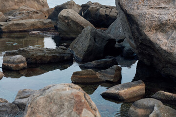 Canvas Print - Tranquil ocean scene with clear water, rocks, and boulders scattered along the shore