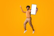 © Prostock-studio - Everything is gonna be allright. Active african man gesturing peace while jumping in the air, orange background