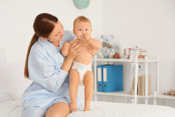 Wall Mural - Young mother with her newborn baby sitting on bed in maternity hospital