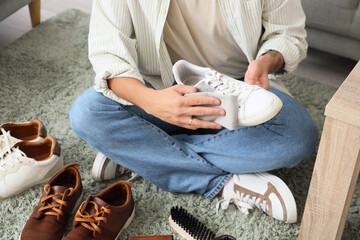 Wall Mural - Young man cleaning white sneaker at home, closeup