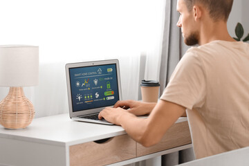 Sticker - Young man using laptop with smart home application at table in room