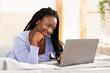 © Prostock-studio - Smiling Afro Student Girl Using Laptop Making Video Call Lying In Bed In Cozy Bedroom. Weekend Morning Concept. Selective Focus