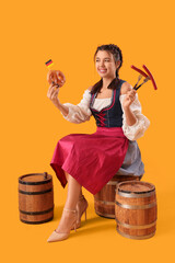 Canvas Print - Young Octoberfest waitress with traditional German food sitting on barrel against yellow background