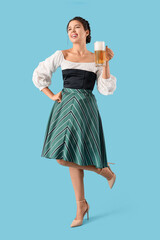 Canvas Print - Young Octoberfest waitress with beer on blue background