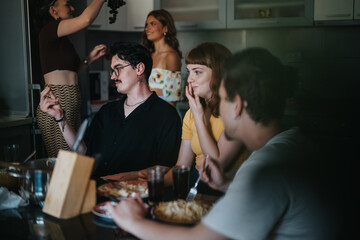 Poster - A group of friends having a casual meal in a home kitchen, sharing laughter and enjoying each other's company in a relaxed setting.