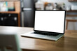© NAMPIX - Mockup blank white screen laptop computer on wooden table in home office room.