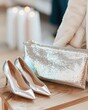 © Ryzhkov - Elegant Metallic Accessories on Wooden Table - Stylish Sequined Clutch and Heels in Trendy Fashion Display