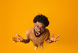 © Prostock-studio - Top view of african american indignant man wearing glasses, raising hands and screaming, full body over orange background