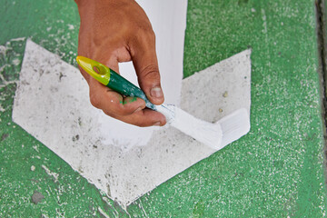 Cropped hand of man painting on footpath