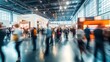 © CStock - A dynamic scene at a busy trade fair with blurred figures of people networking and interacting around modern exhibition booths, capturing the energy and movement of a vibrant business event