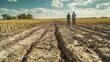 © Worakit - Farmers standing in drought affected field, observing dry, cracked soil and barren crops. scene reflects challenges of agriculture in arid conditions
