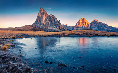 Wall Mural - Frozen small lake at the foot of Ra Gusela peak. Cold morning scene of Dolomite Alps. Majestic autumn sunrise on Giau pass, Italy, Europe. Beauty of nature concept background.