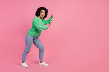 Portrait of young charming woman with chevelure in green stylish sweatshirt pushing copyspace isolated on pink color background