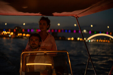 Couple on a nighttime boat ride with city lights