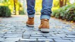 © Tmack - A man walks on a cobblestone path with fall leaves, wearing brown boots and jeans.