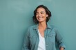 © Markus Schröder - Portrait of a smiling woman in her 40s sporting a versatile denim shirt while standing against soft teal background