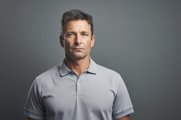 Canvas Print - Portrait of a glad man in his 40s wearing a breathable golf polo while standing against soft gray background