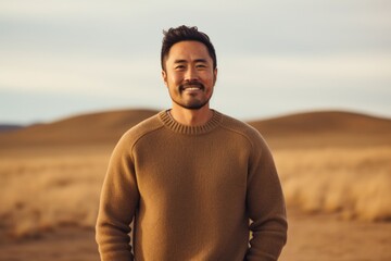 Poster - Portrait of a content asian man in his 30s wearing a cozy sweater isolated on soft brown background