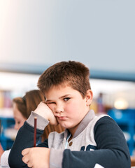 Poster - Bored, education and portrait of boy student in classroom of school for child development or study. Learning, notebook and writing with unhappy learner kid at desk in class for future, growth or test