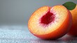 © Helois - Close-up of a sliced peach with a leaf on a gray background.