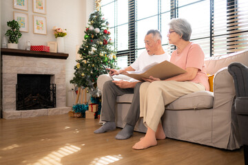 Wall Mural - Grandfather and grandmother are reviewing the expenses and the food menu to host their children and grandchildren during the Christmas holiday at home