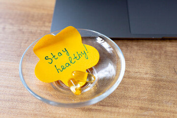 A colorful note encourages wellness placed on a clear dish surrounded by vibrant greenery