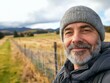 © Nataliia_Trushchenko - A man with a gray hat and beard is smiling and posing for a picture. The image has a peaceful and relaxed mood, as the man is standing in a field with a fence in the background