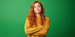 © Iryna - A woman with red hair is wearing a yellow sweater and is smiling. She is standing in front of a green background