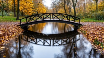 Canvas Print - Small bridge over a stream in an autumn park, surrounded by bright foliage and reflected in the water 