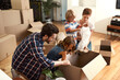 © StarDweller/peopleimages.com - Boxes, new home and parents with kids, help and bonding together with real estate. Happy family, apartment and cardboard with mother, father and childhood with property, cheerful and moving in lounge