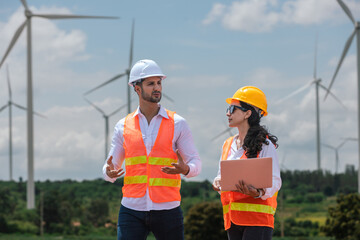 Fototapete - Team engineer wearing safety uniform holding laptop discussed plan about renewable energy at station energy power wind. technology protect environment reduce global warming problems.