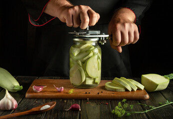 A manual seaming key in the hands of a chef preserving zucchini with aromatic spices in a restaurant kitchen.