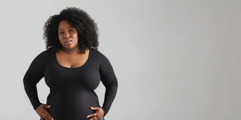 Sticker - A woman with a large bust stands in front of a gray background. She is wearing a black shirt and she is posing for a photo. Concept of confidence and self-assurance, as the woman stands tall