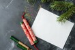 © Ari - A flat lay of traditional Chinese firecrackers and a blank card, placed on a dark surface with festive pine branches.