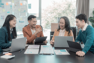 Group of Asian business people in conference room for business presentation or seminar. Documents have financial or marketing figures, graphs and charts. There is a laptop to analyze company stocks.