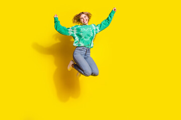 Canvas Print - Full length photo of lucky positive woman wear green sweatshirt jumping high rising fists empty space isolated yellow color background