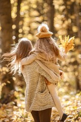 Wall Mural - Mother and her daughter playing and having fun in autumn forest