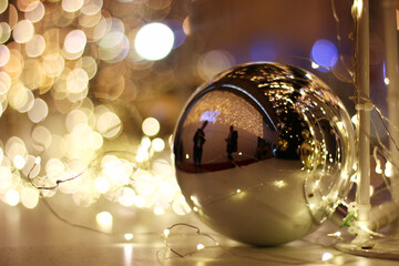 Christmas gold ball in a business center with people reflected on a gold background