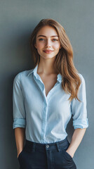 Sticker - Portrait of a smiling young businesswoman posing with hands in pockets against a gray wall