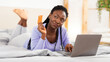 © Prostock-studio - Online Shopping. African American Lady Holding Credit Card Using Laptop Buying Things On Internet Lying In Bed Indoor