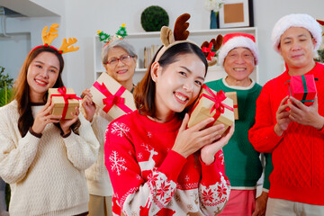 Young woman holding gift box smiling celebrating Christmas with family.